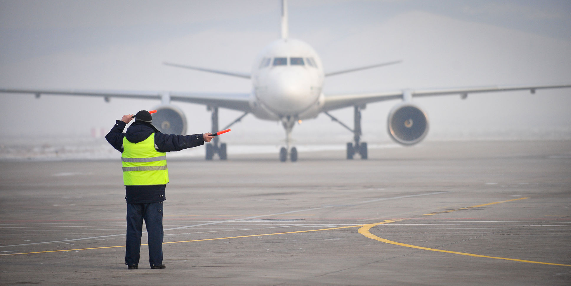 airport worker directing an airplane as it arrived